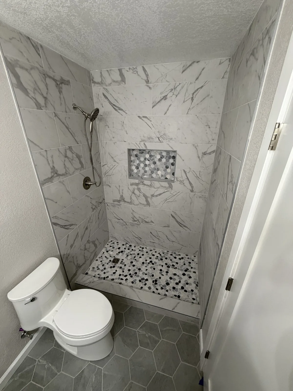 Finished walk-in shower with marble-look tile and mosaic floor in Modesto